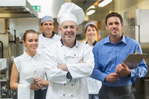 26768946 - head chef posing with the team behind him in a profesional kitchen