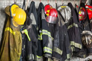 44186423 - firefighter suits and helmets hanging at fire station